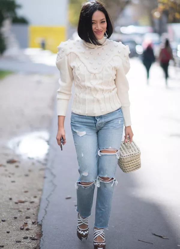 Девушка в рваных джинсах и молочном свитере