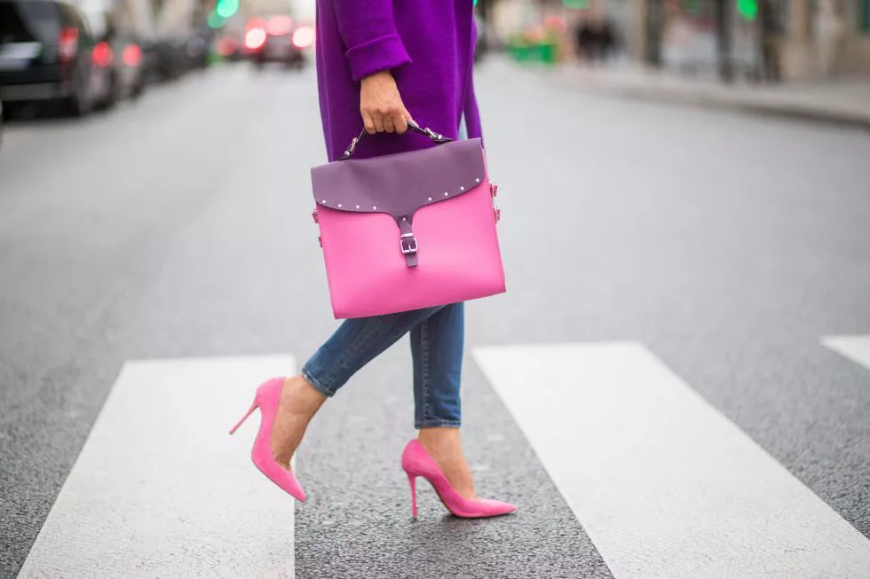 Блогер в розовых туфлях, сумка чемодан, джинсы и фиолетовое пальто