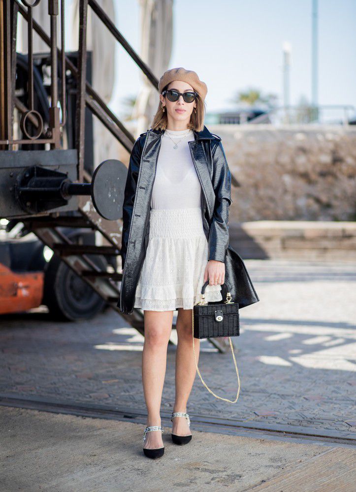 Девушка с легком белом платье, кожаный плащ, береь и черная соломеная сумка