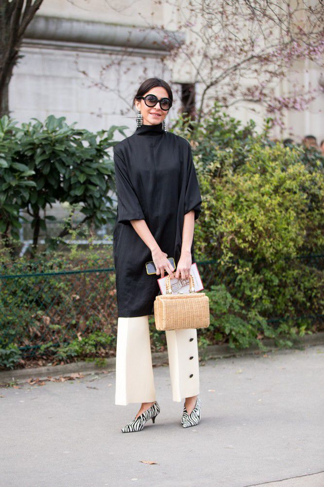 Девушка в черном платье, белые брюки, туфли в полоску и соломенная сумка