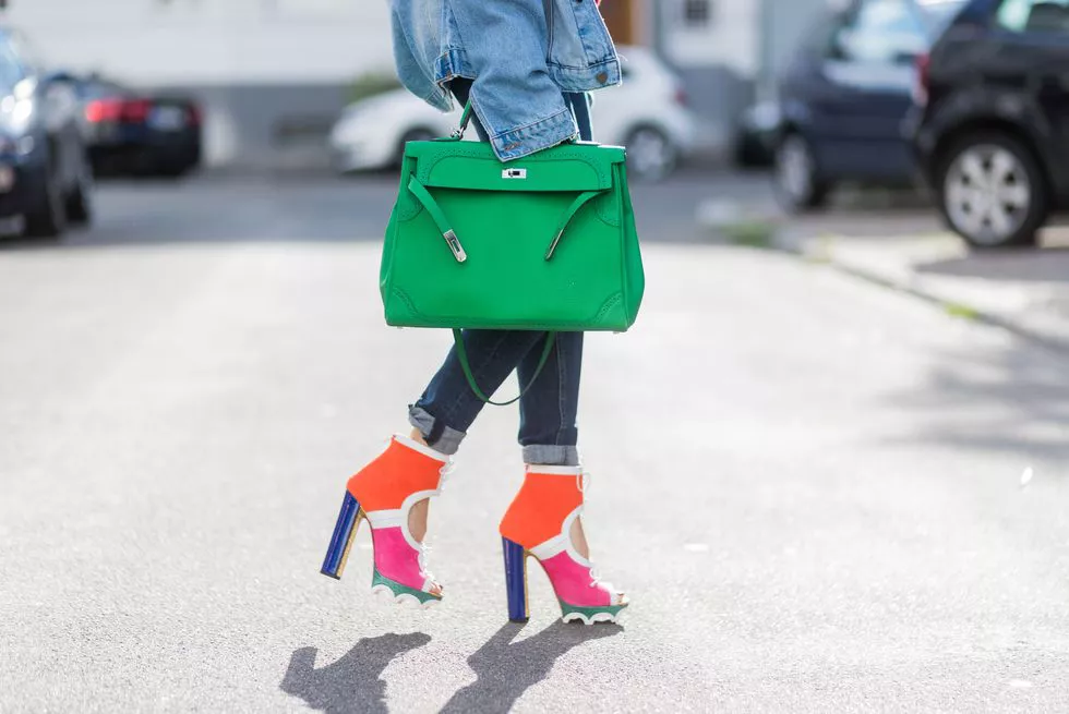 Девушка в джинсовой куртке, разноцветные туфли и зеленая сумка