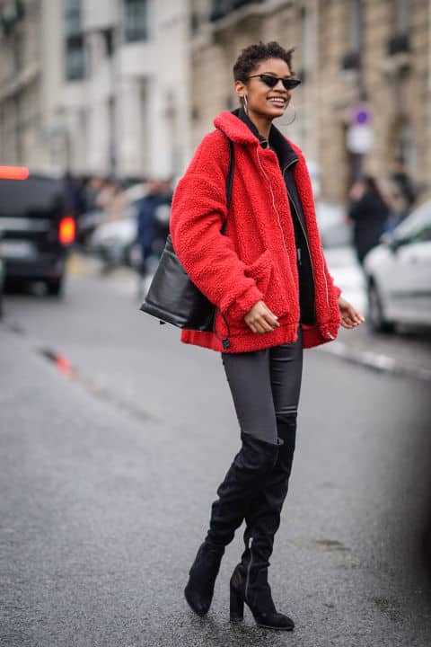 Девушка в красной куртке, черные ботфорты и солнцезащитные очки