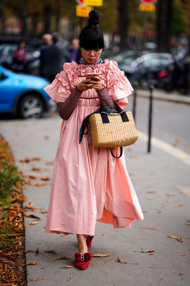 Девушка в розовом платье оверсайз с рюшами и соломеная сумка