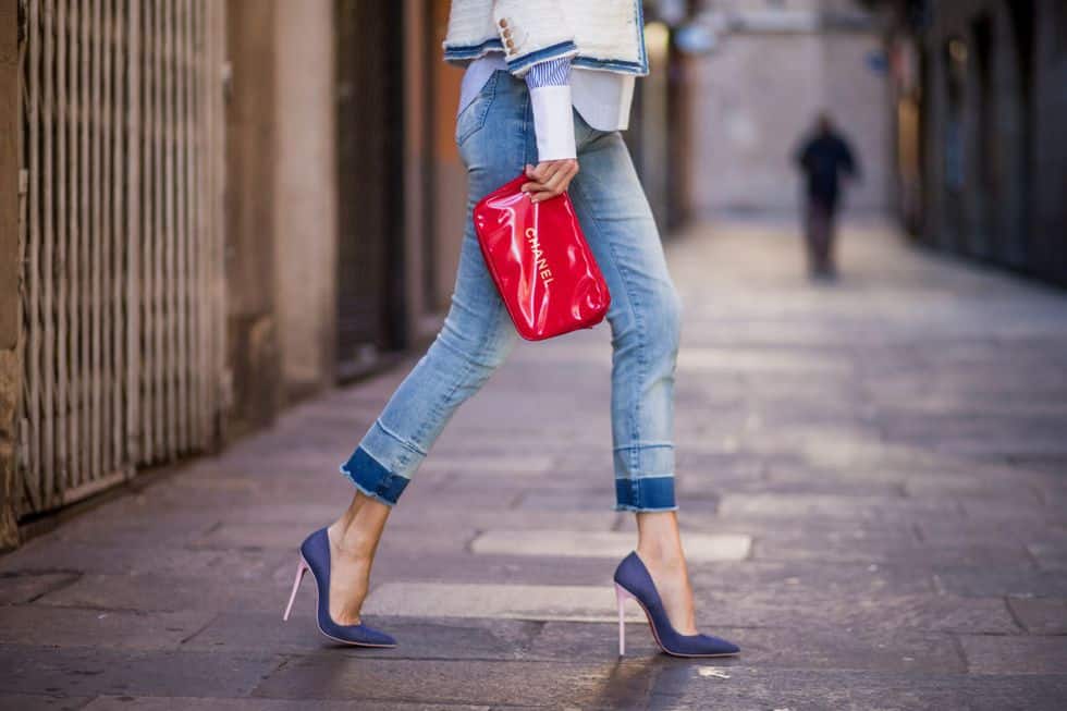 Девушка в укороченных джинсах, синих туфлях на шпильке и красная сумочка