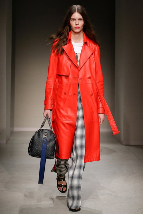 Модель с модного показе Trussardi в красном кожаном плаще и брюках в клетку