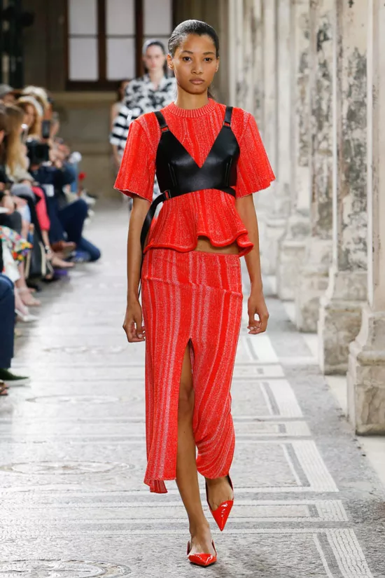 Модель в красной блузке с черным корсетом и красная юбка миди с разрезом от Proenza Schouler