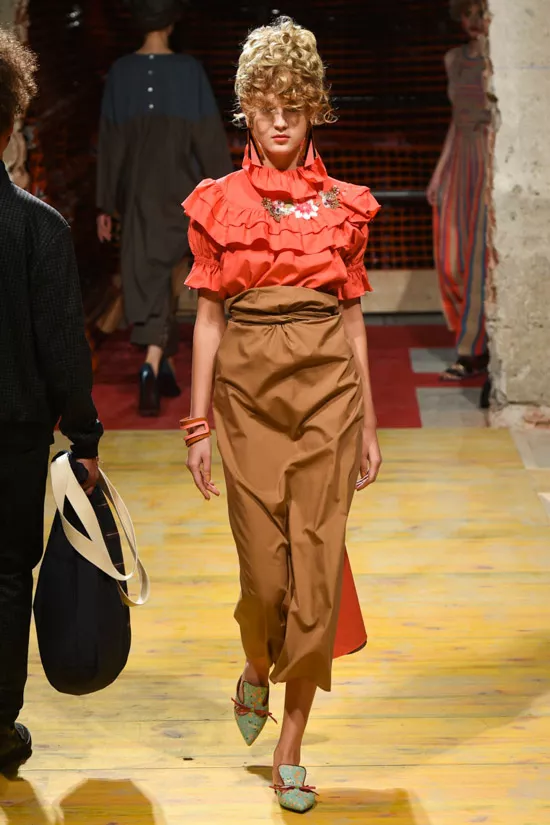Модель в красной блузке с рюшами и юбке миди песочного цвета от Antonio Marras