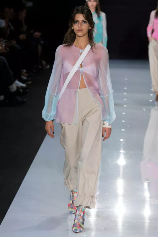 Модель в прозрачной блузке без воротник и светлые брюки от Emporio Armani