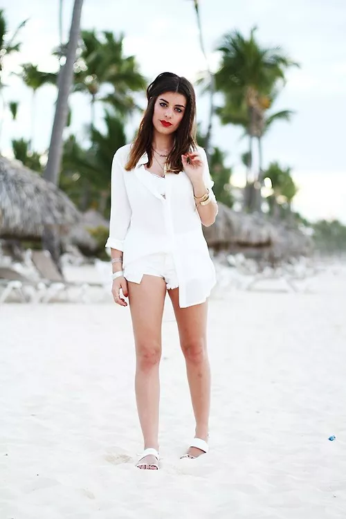 Девушка на пляже в белой рубашке и мини шортах