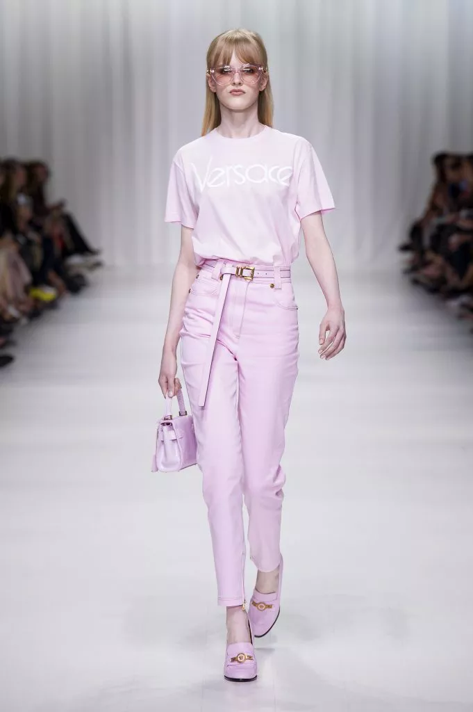 Модель в розовой футболке с надписью и светло розовые брюки