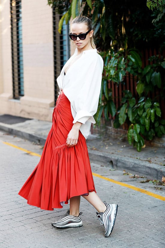 Девушка в белой блузке и красной динной юбке с воланами, кроссовки