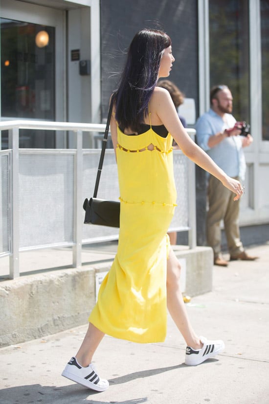 Девушка в белых кедах с черными полосками и желтое платье комбинация на бретельках