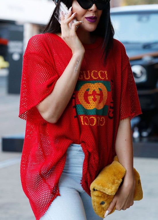Девушка в красной футболке от Gucci и белых джинсах
