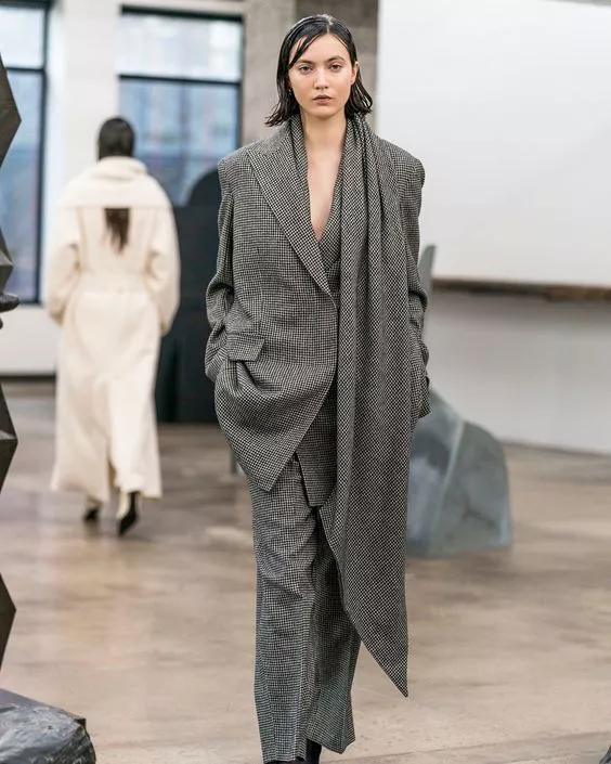 Модель в твидовых брюках и ассиметричном пальто, модные тенденции