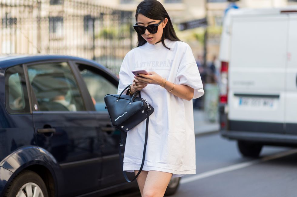 Девушка в белой футболке оверсайз, черной сумочке и солнцезащитных очках