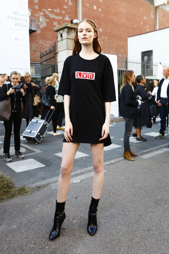Девушка в черной футболке оверсайз с логотипом и черных ботильонах