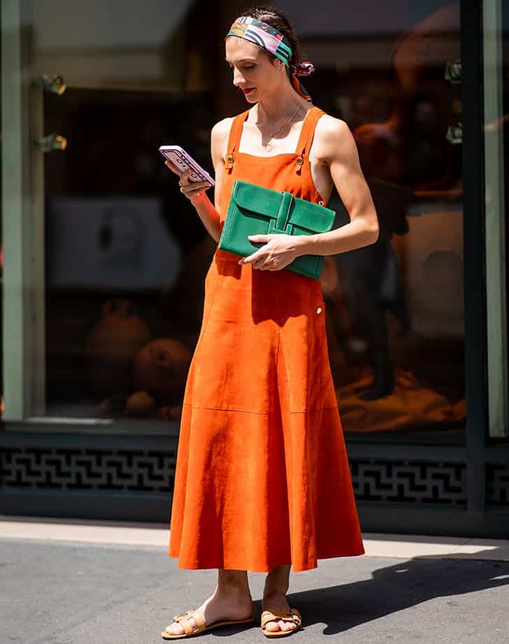 Девушка в оранжевом сарафане макси, зеленый клатч и сланцы