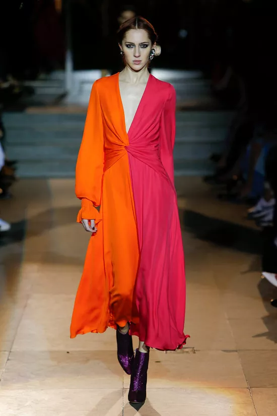 Модель в красно оранжевом платье с длинными рукавами от Carolina Herrera