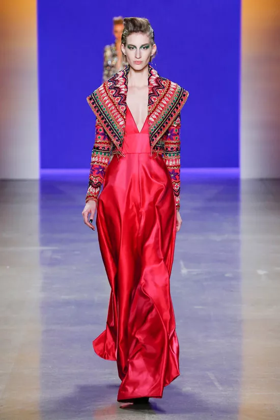 Модель в красном атласном плтье макси и пестрой кофте от NaeemтKhan