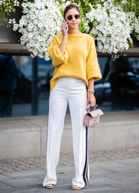 Девушка в белых брюках с лампасами, желтый свитер и сумочка