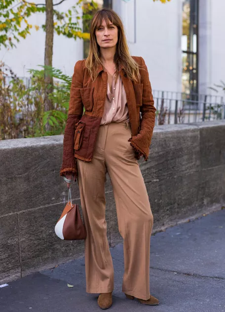 Девушка в бежевых брюках, блузка и коричневая куртка