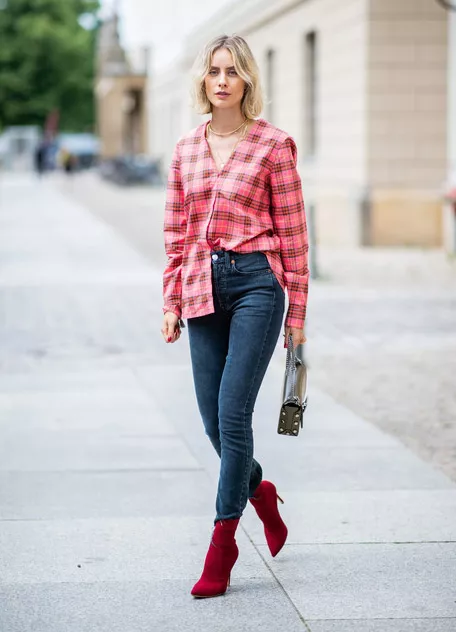 Девушка в джинсах скинни, розовая рубашка в клетку и красные ботильоны