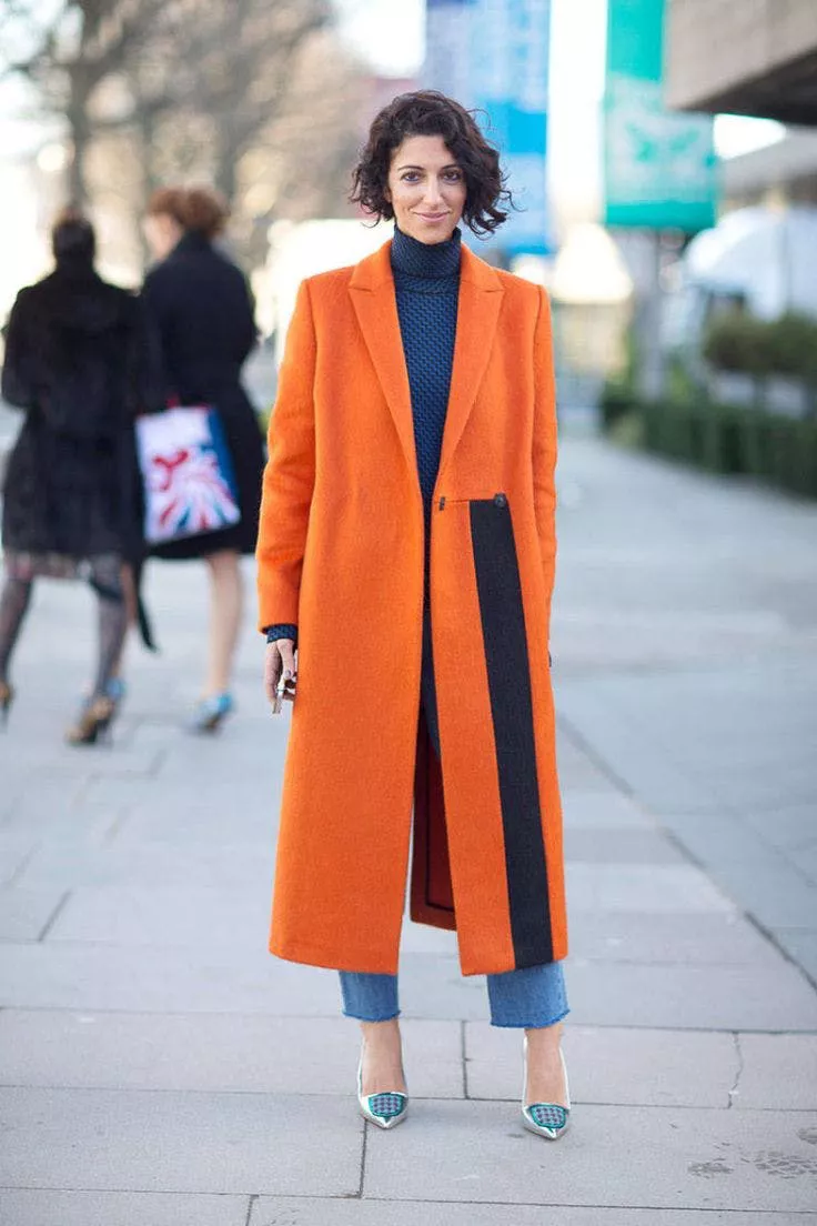 Девушка в джинсах и оранжевом пальто