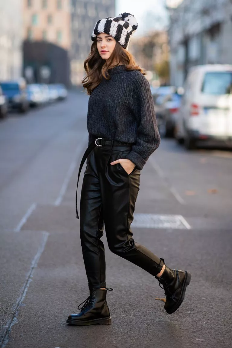 Девушка в кожаных черных брюках, свитер и ботинки на шнурках