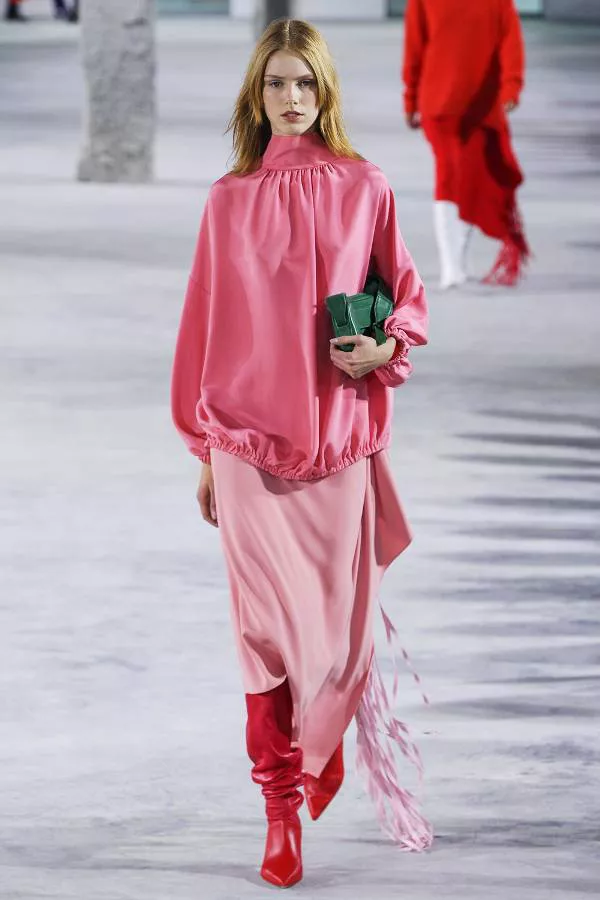 Модель в розовой юбке и блузке и красные сапоги