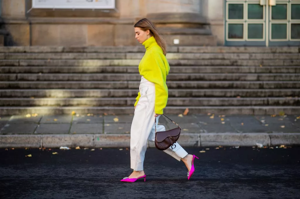 Девушка в белых брюках, неоновый свитер и розовые туфли