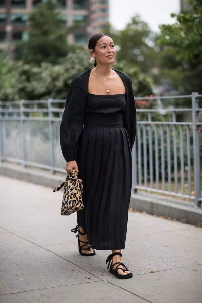Девушка в черном платье макси, лепардовая сумочка и сандалии на плоской подошве