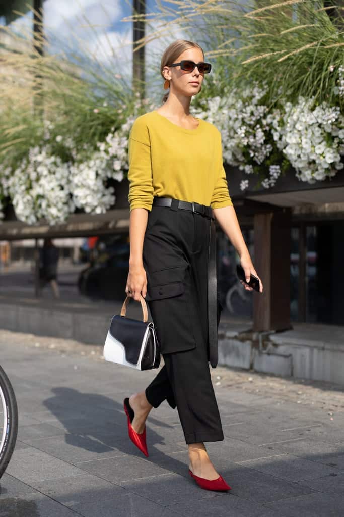 Девушка в черных брюках, желтый джемпер и красные туфли