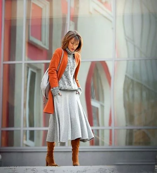 Девушка в серой юбке миди, свитер и оранжевое пальто