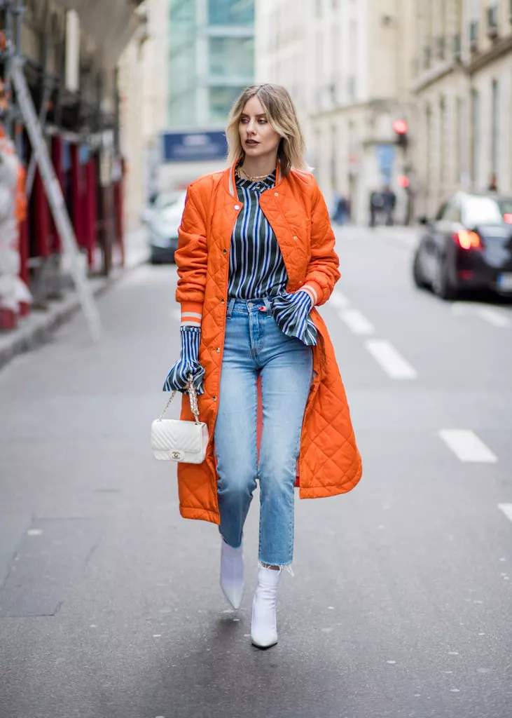 Девушка в укороченных джинсах, оранжевая куртка и белые ботильоны