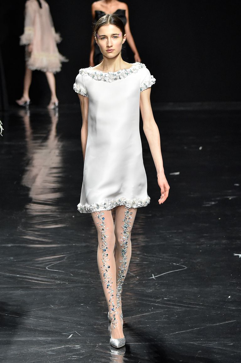 Модель в белом мини платье и колготках с украшениями