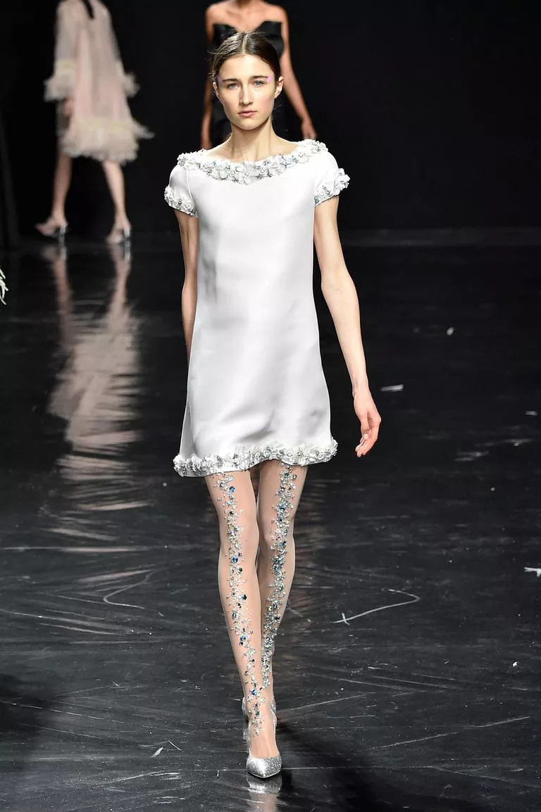Модель в белом мини платье и колготках с украшениями