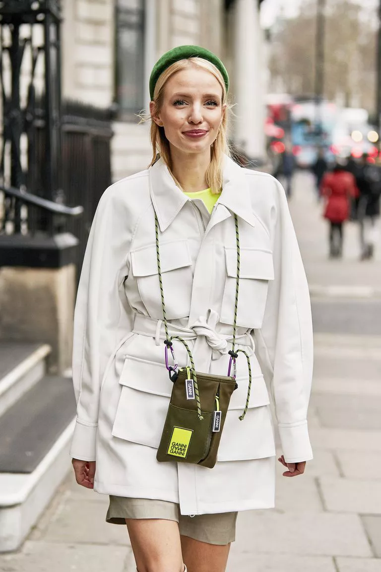 Девушка в белой куртке в стиле мидитари и маленькая зеленая сумочка на шее