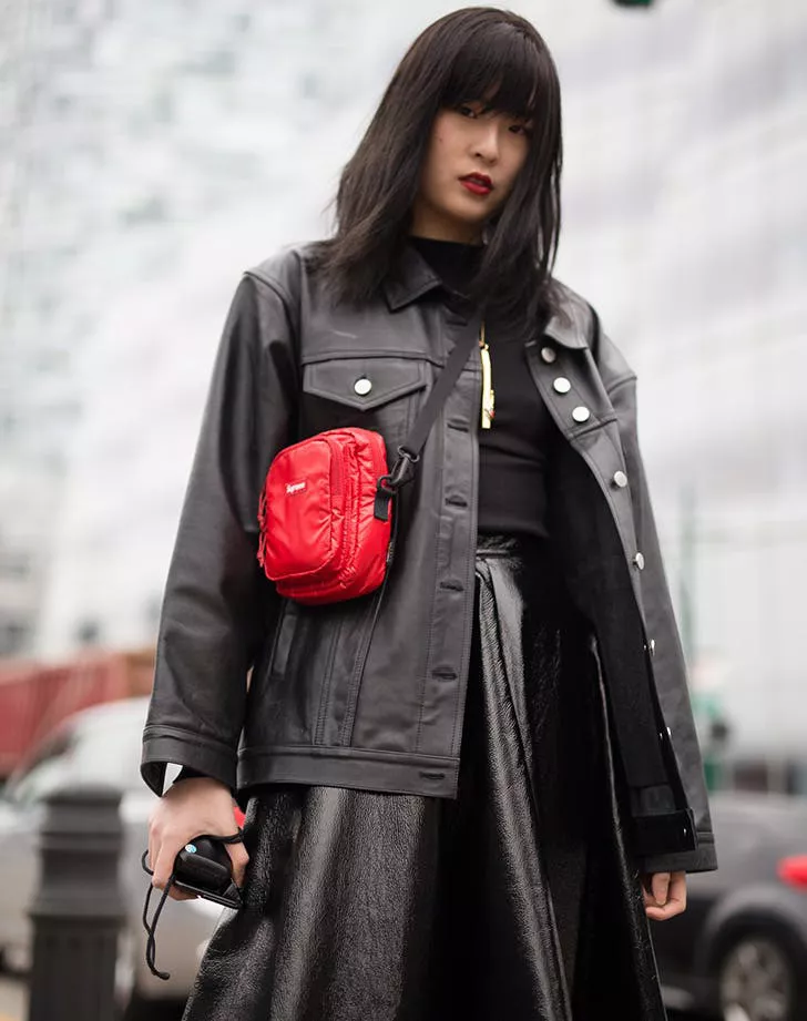 Девушка в черной юбке миди, кожанная куртка и красная сумочка