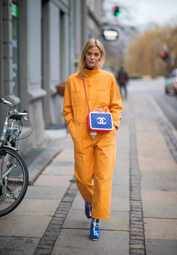 Девушка в оранжевом комбинезоне, синие ботильоны и сумочка