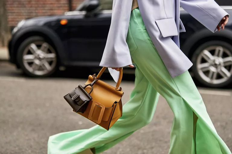 Девушка в широких зеленых брюках, коричневая сумка и маленькая сумочка