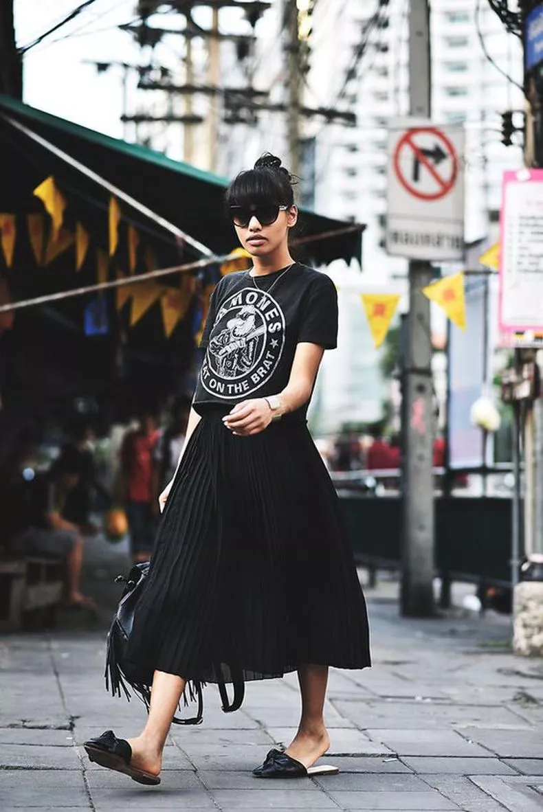 Девушка в черной плиссированной юбке и футболка с принтом
