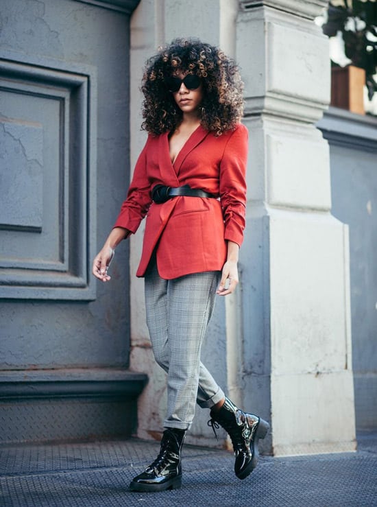 Девушка в серых брюках в клетку, красный пиджак с ремнем и ботинки