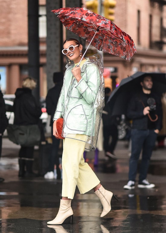 Девушка в укороченных брюках, прозрачный плащ и красный зонт