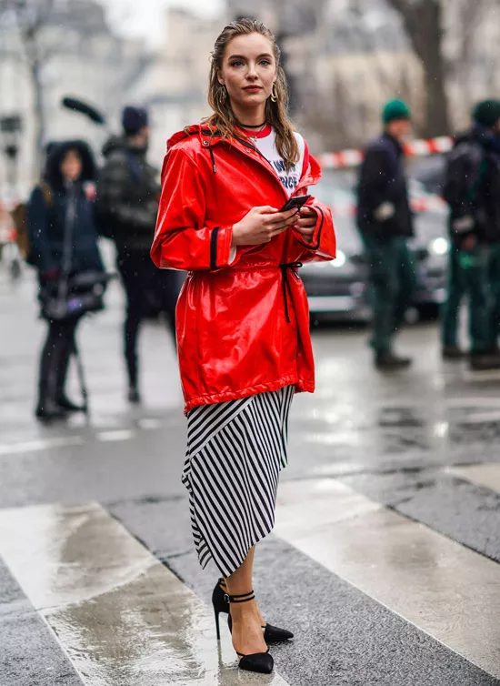 Девушка в юбке в полоску, красная лакированная куртка и черные туфли