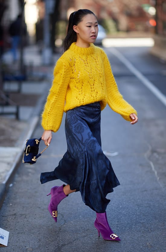 Девушка в желтом свитере, синяя юбка и фиолетовые ботильоны