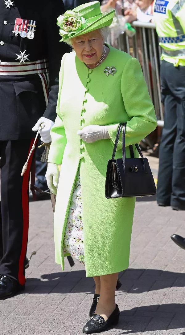 Королева Елизавета в зеленом пальто и шляпе, черные туфли и сумочка