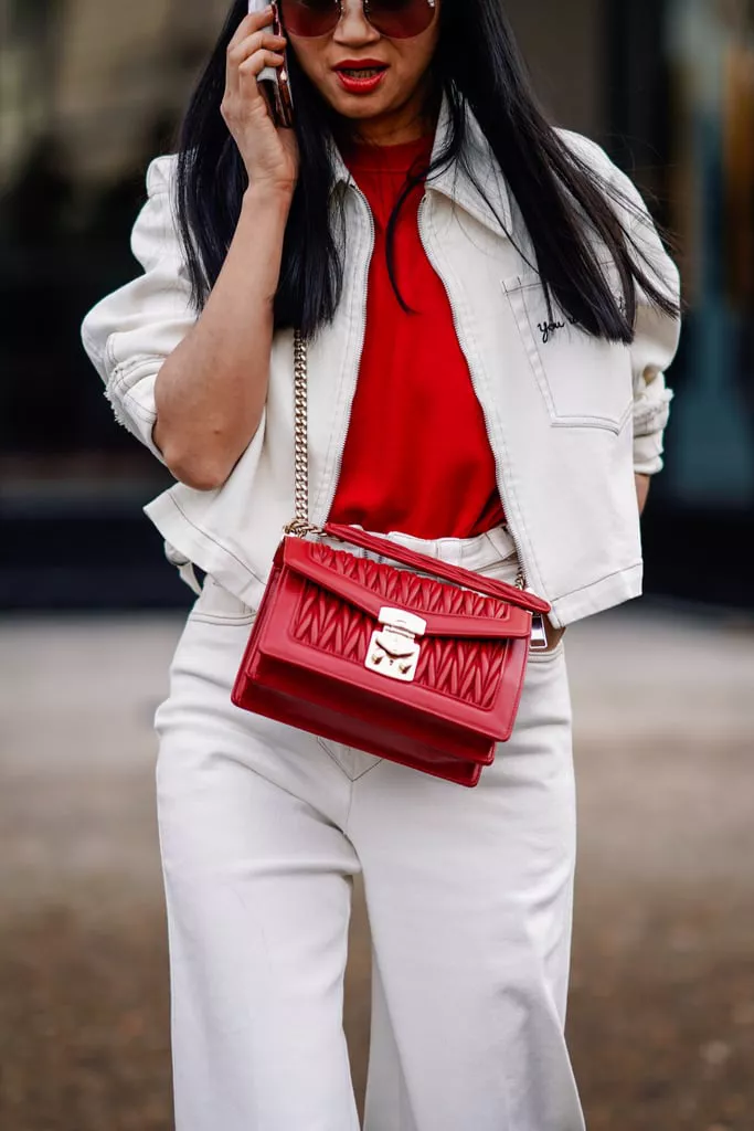 Девушка в белых широких джинсах, куртка и красная футболка и сумка