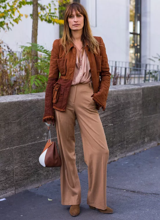 Девушка в бежевых брюках, блузка и коричнева куртка