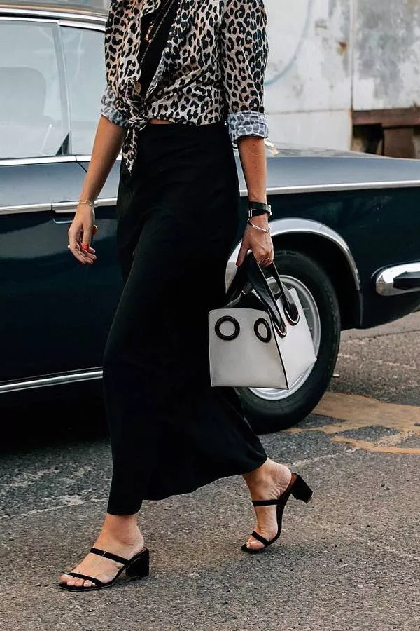 Девушка в черной юбке макси, рубашка с леопардовым принтом и черные сандалии