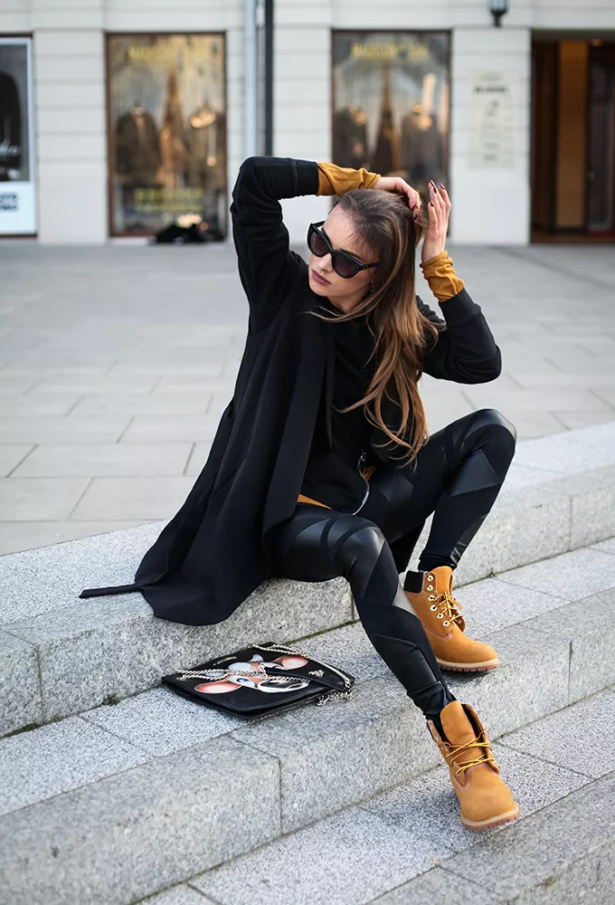 Девушка в черных леггинсах, кардиган и коричневые ботинки
